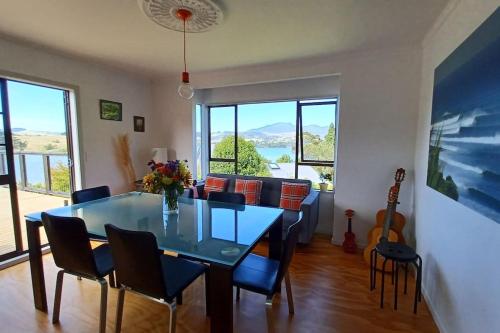 a dining room with a glass table and chairs at Bay and Karioi view in town in Raglan