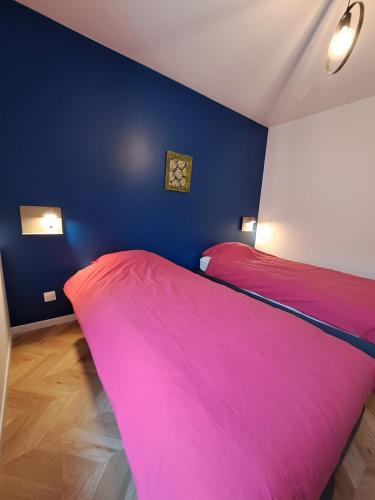 a bedroom with two beds and a blue wall at A la maison de Jaulny in Jaulny
