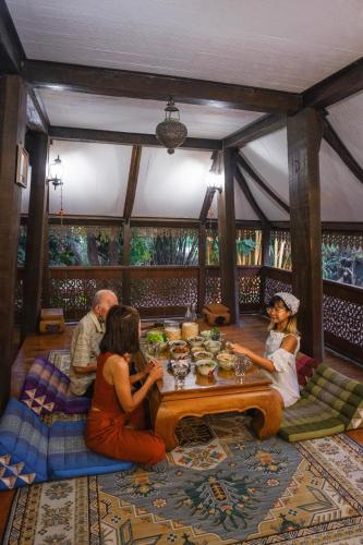 a group of people sitting around a table in a restaurant at Ban MaeBo Local Stay in Ban Nong Han