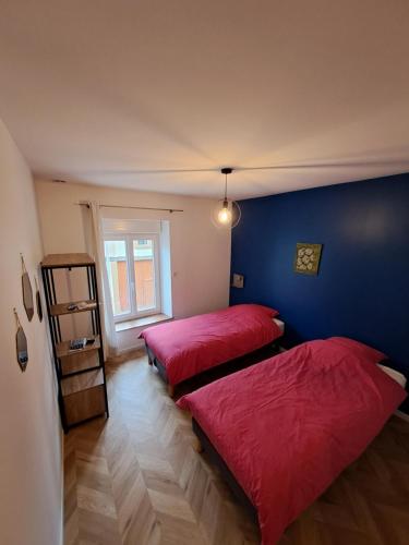 two beds in a room with red sheets at A la maison de Jaulny in Jaulny