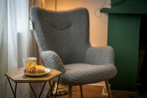 a chair and a table with a bowl of oranges at Vale House By EDEN Accommodation - 2 Bedroom Whole House, Sleeps 4 - NEWLY RENOVATED in Kettering