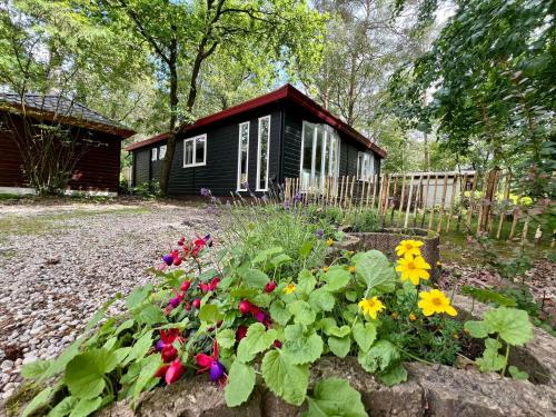 a garden with flowers in front of a cabin at Kindvriendelijk sfeervol vakantiehuis Bosgeneugte bij zwembad op de Veluwe in Doornspijk