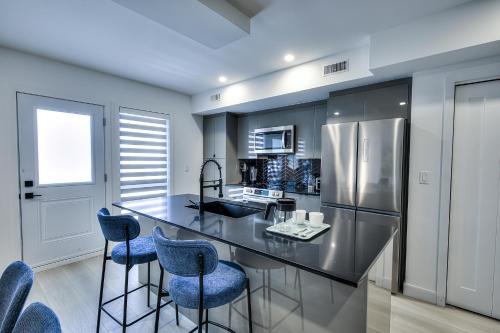 a kitchen with a black counter and blue bar stools at Montreal Restful Nights, Adventure Days await! in Montréal