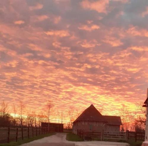 a barn under a cloudy sky at sunset at B&B Haras de la Cour Fleury in Saint-Michel-de-Livet