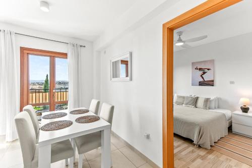 a white room with a table and chairs and a bed at Apartment Theia with sea and sunset views, the Resort in Aphrodite Hills in Kouklia