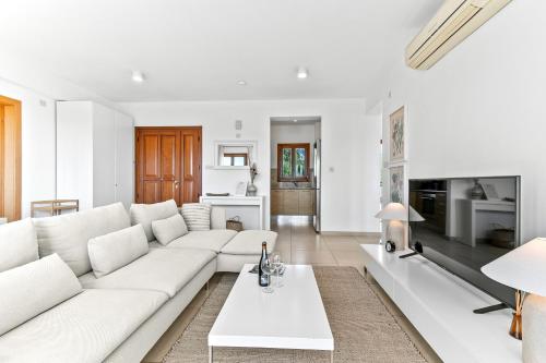 a white living room with a white couch and a table at Apartment Theia with sea and sunset views, the Resort in Aphrodite Hills in Kouklia