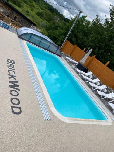 a swimming pool with a lounger and two chairs at BrickWood in Verkhniy Koropets