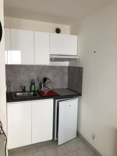 une cuisine avec des armoires blanches et un évier dans l'établissement Très beau studio près du centre ville, à Nîmes