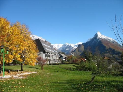 a house in a field with mountains in the background at Apartments Kaninska Vas in Bovec