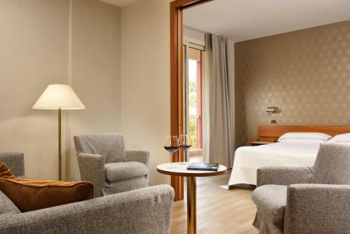 a hotel room with a bed and two chairs and a table at Hotel Continental Wellness & Spa in Sirmione