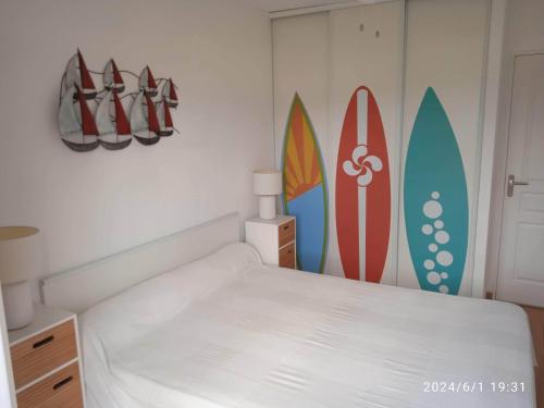 - une chambre avec un lit et des planches de surf sur le mur dans l'établissement Joli T2 Socoa Urrugne 900m de la mer, à Urrugne