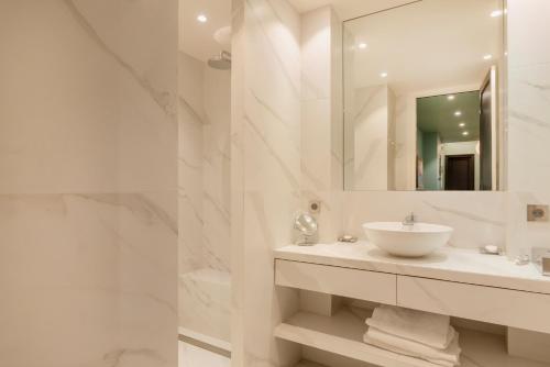 une salle de bain blanche avec un lavabo et un miroir dans l'établissement Paris Wagram Design Residence, à Paris