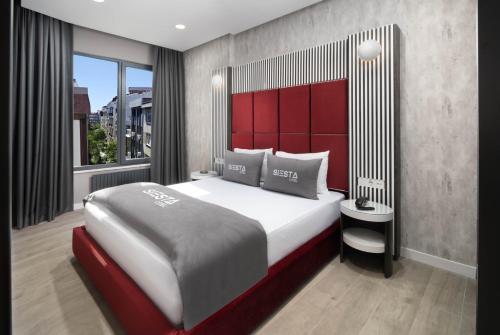 a bedroom with a large bed with a red headboard at Siesta Hotel Bakırköy in Istanbul
