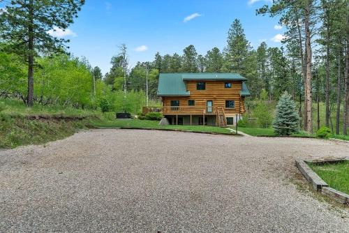 a log home in the woods with a gravel driveway at Peaceful Valley Hideaway in Rapid City