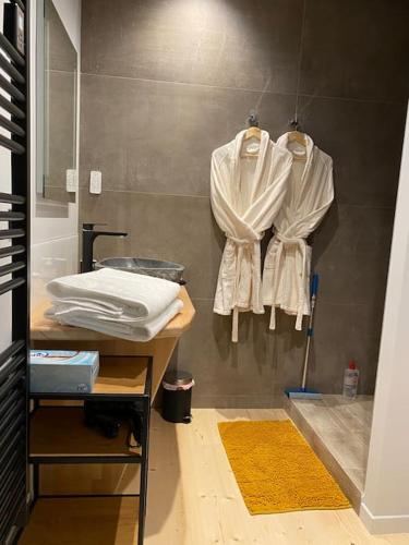 La salle de bains est pourvue de serviettes blanches accrochées au mur. dans l'établissement L'Appartement de Maman, Jacuzzi & Hammam privé, à La Bresse