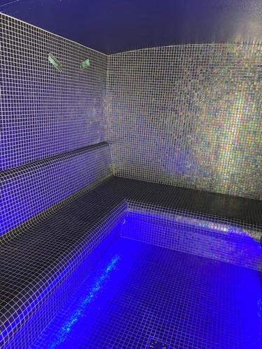 La salle de bains est pourvue d'une baignoire avec des lumières violettes. dans l'établissement L'Appartement de Maman, Jacuzzi & Hammam privé, à La Bresse
