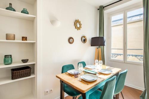 une salle à manger avec une table en bois et des chaises vertes dans l'établissement Geranimus Court of Scents, à Versailles