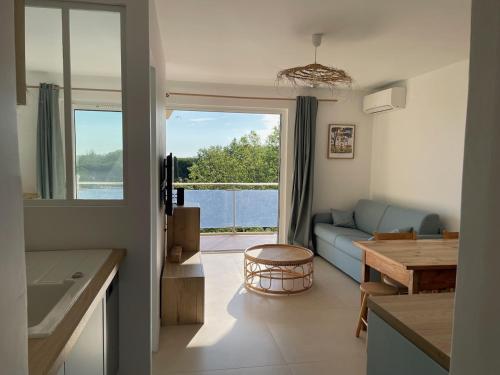 une cuisine et un salon avec un canapé et une table dans l'établissement Les pins du Capri - Meublé de tourisme 3 étoiles, à La Grande Motte