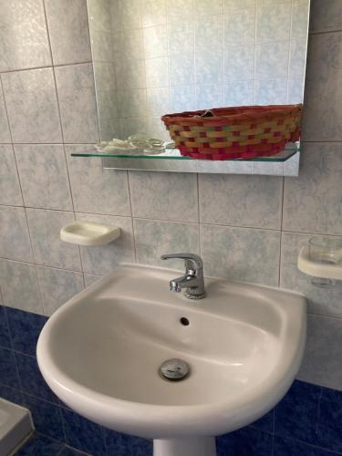 a white sink in a bathroom with a basket on a shelf at Ammodares in Lixouri