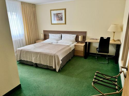 a bedroom with a bed and a desk and a chair at Hotel Residenz Stockstadt in Stockstadt am Main