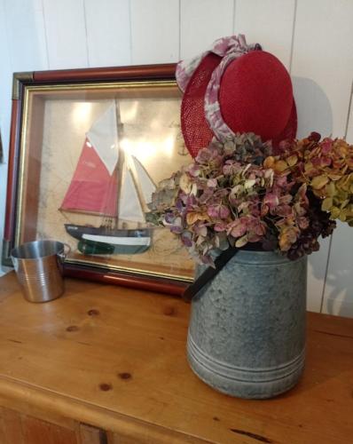 a vase with a hat and flowers in front of a mirror at Les chambres d'hôtes Le Val d'Honfleur in Équemauville