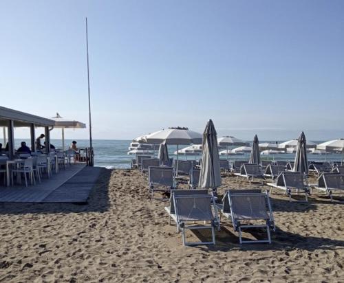 a group of chairs and umbrellas on a beach at Appartamento al mare in Eraclea Mare