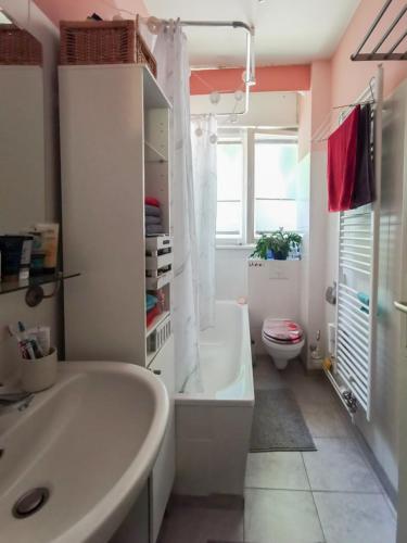 een witte badkamer met een bad en een toilet bij Cosy Room in Our Apartment in Berlijn