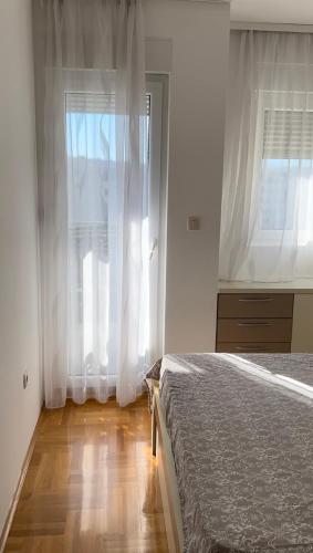 una camera con letto e finestra con tende bianche di Apartment Shine a Podgorica