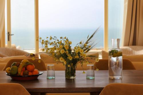 a table with a vase of flowers and a bowl of fruit at ALNA mogador in Akermoud