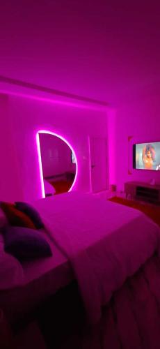 a bedroom with a bed with a pink lighting at 3Bed Profssnal & Family Friendly with Swimming pool, Work Stns, PS5, Gym & near Beaches in Lagos