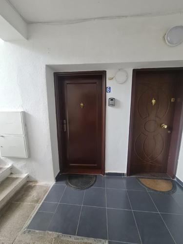 zwei braune Türen in einem Zimmer mit Fliesenboden in der Unterkunft Egi's Apartment in Shkodra