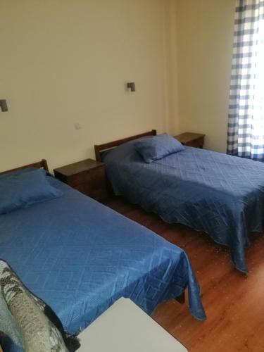 two beds in a bedroom with blue sheets at Casa da Estação in Sines