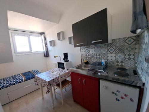 - une petite cuisine avec une petite table et un lit dans l'établissement Studette éco près du phare, à Calais