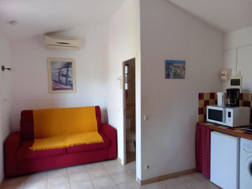 - un salon avec un canapé rouge et jaune dans l'établissement mini villa studio 1 pièce 21 m2 pour 2 personnes piscine partagée climatisation, à Porto-Vecchio