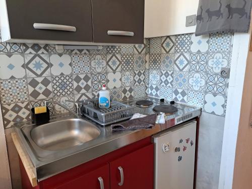 une petite cuisine avec un évier et une cuisinière dans l'établissement Studette éco près du phare, à Calais