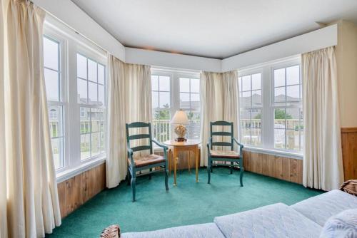 a bedroom with two chairs and a table and windows at The Shabedge at Ships Watch in Duck