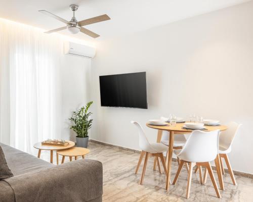 een woonkamer met een tafel en stoelen en een televisie bij Minimalist apartment near the airport and the city center in Kanálion