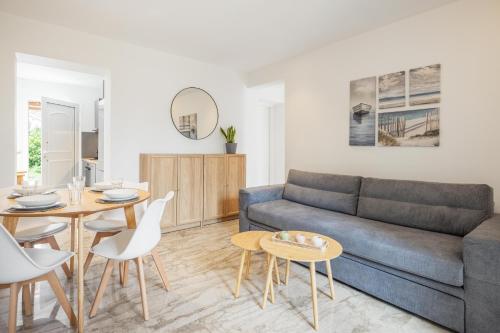 een woonkamer met een bank, een tafel en stoelen bij Minimalist apartment near the airport and the city center in Kanálion