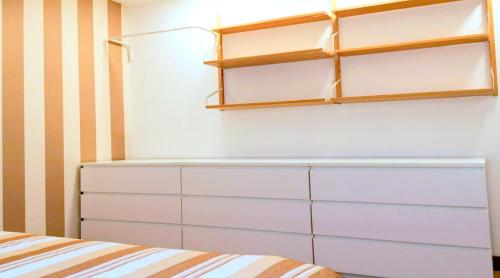 a bedroom with a white refrigerator and shelves at CQ Coimbra in Coimbra