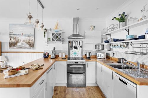 a kitchen with white cabinets and wooden counter tops at The Boathouse - Panoramic Sea View Retreat, near Town, Marina & Beach, with Parking in Torquay
