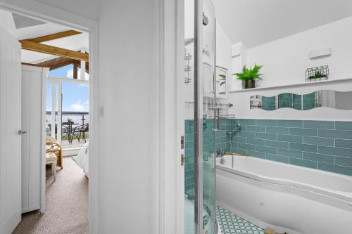 y baño con bañera y ducha con azulejos azules. en The Boathouse - Close to marina, beach and town centre, en Torquay