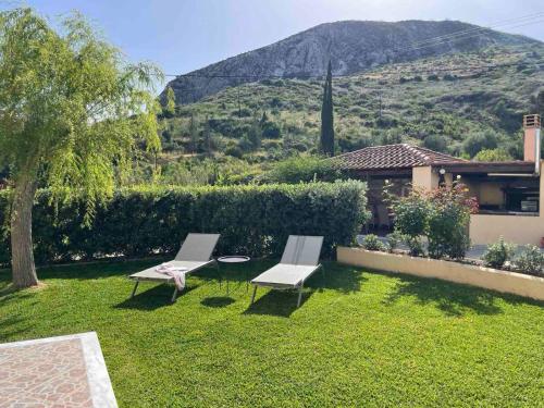 a yard with two chairs and a house with a mountain at Stefanos Home in Katelios