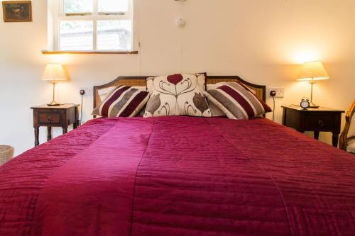 a bedroom with a large bed with a red bedspread at The Doghouse near Silverstone in Buckingham