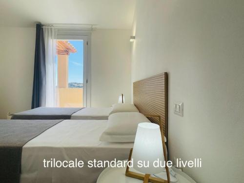 a bedroom with two beds and a window at Appartamenti Shardana in Villasimius