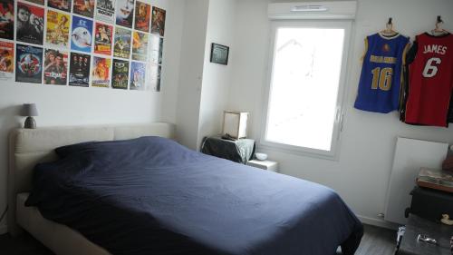 - une chambre avec un lit et des jerseys accrochés au mur dans l'établissement Appartement cosy avec terrasse, 2 chambres, à Noisy-le-Sec