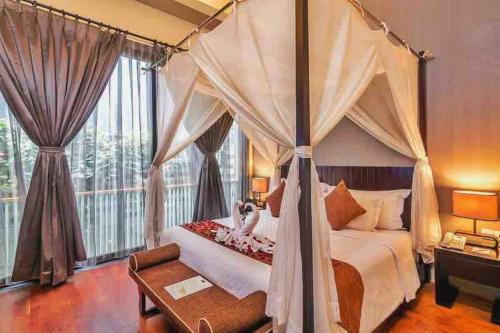 a bedroom with a canopy bed and a large window at Venus- 1br pvt pool villa in kuta By iLys Collection in Kuta