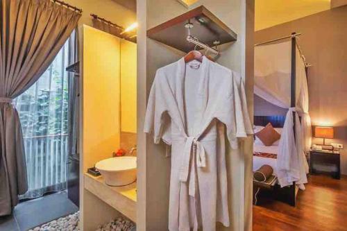 a bathroom with a robe hanging on a wall at Venus- 1br pvt pool villa in kuta By iLys Collection in Kuta