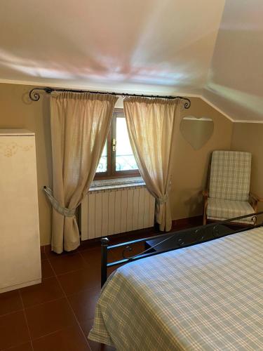a bedroom with a bed and a chair and a window at Green Quiet Affittacamere in Pignone