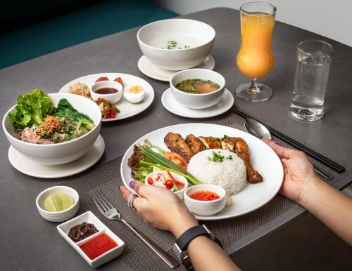 a table with plates of food and a person holding a plate at Chaiya Palace Hotel in Phnom Penh