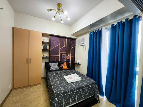 - une chambre avec un lit et des rideaux bleus dans l'établissement Executive Studio Palladium, à Iloilo